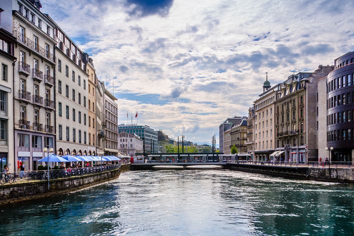 Die Rhône fließt zwischen historischen Gebäuden und Brücken durch das lebendige Zentrum von Genf.