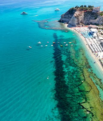 Blick aus der Luft auf den Strand von Tropea mit seinem kristallklaren Wasser und der Promenade, Kalabrien, Italien