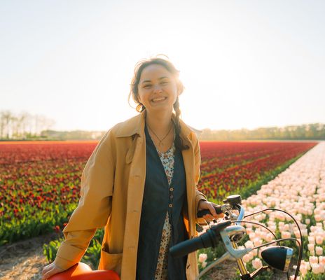 Frau mit Fahrrad vor Tulpenfeld