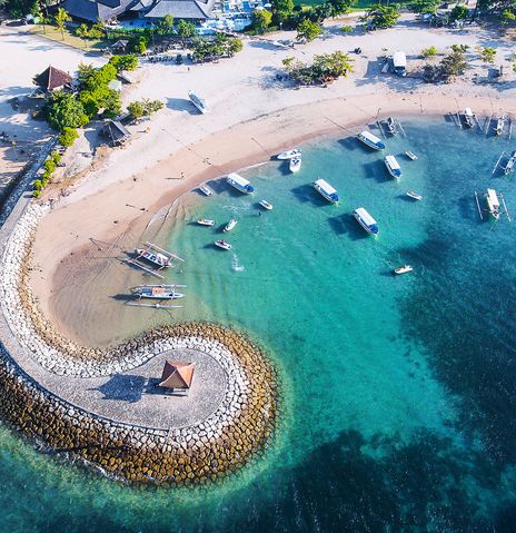Luftaufnahme der geschwungenen Bucht von Nusa Dua mit Booten