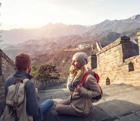 Junges Paar auf der Spitze der Chinesischen Mauer, das die wunderschöne Landschaft von oben betrachtet