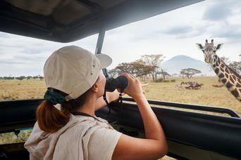 Frau beobachtet Giraffe bei Safari