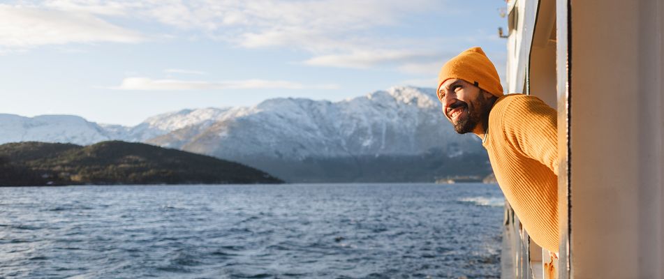 Mann schaut über die Reling eines Flusskreuzfahrtschiffes aufs Wasser