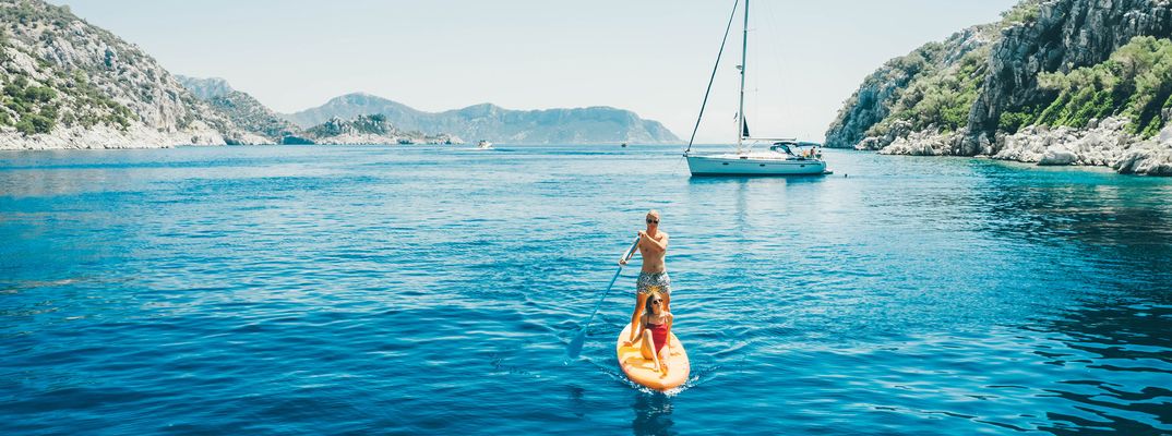 Paar auf einem Stand-up-Paddle in einer türkisblauen Bucht