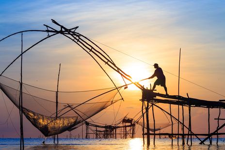 Fischer mit Fischernetzen bei Sonnenuntergang in Kochi