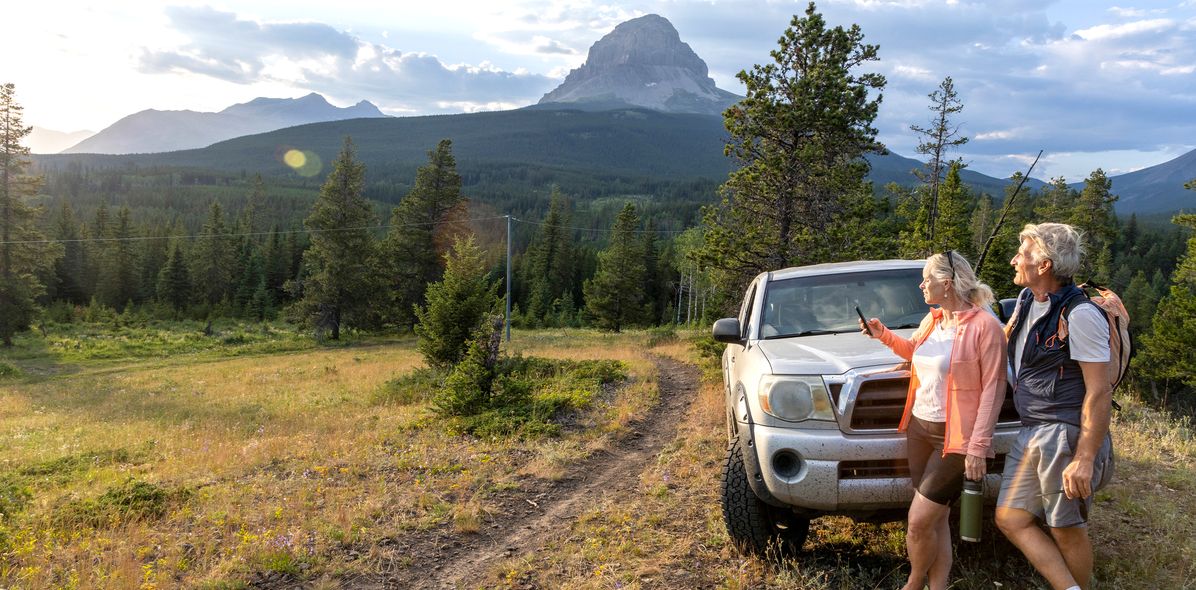 Paar steht an einem Mietwagen gelehnt in Kanada im Bundesstaat Alberta