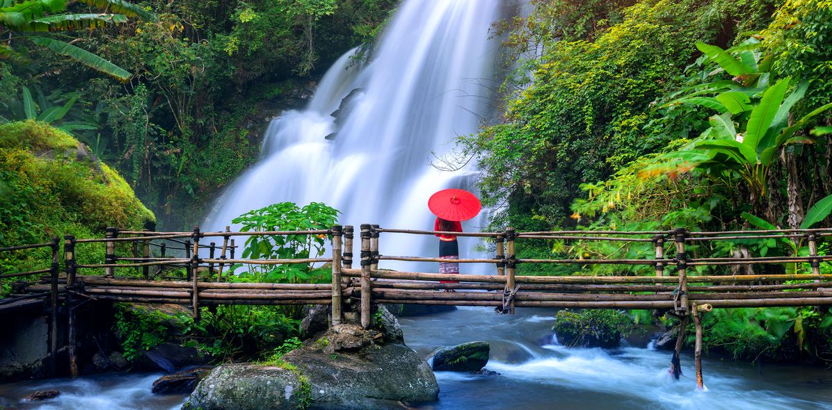 Frau vor einem Wasserfall in Chiang Mai