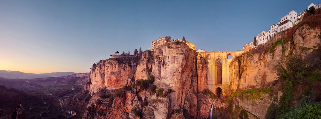 Ronda thront im warmen Abendlicht auf steilen Felsen über der tiefen Schlucht El Tajo in Andalusien.