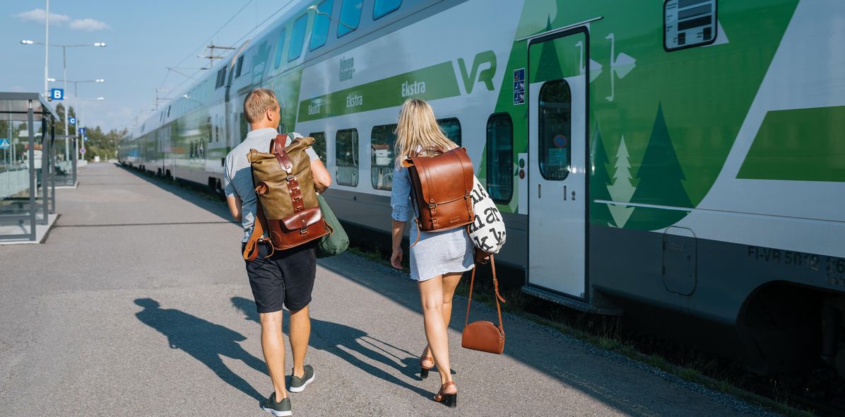 Touristen sind an einem Bahnhof in Finnland und gehen zu ihrem Zug