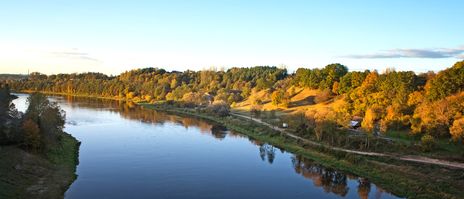 Ruhiger Fluss bei Alytus mit Spiegelung der Bäume und herbstlichen Farben