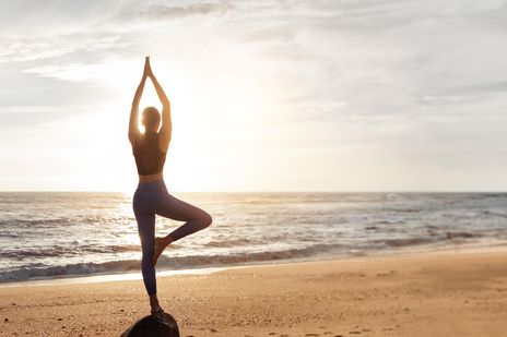 Frau macht Yoga am Strand