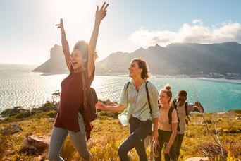 Fröhliche Gruppe beim Wandern mit Ausblick auf das Meer