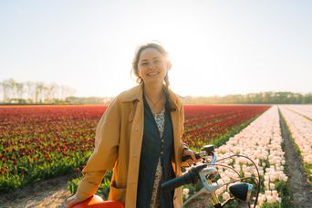 Frau mit Fahrrad vor Tulpenfeld