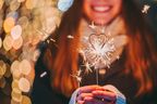 Junge Frau hält Wunderkerze in der Hand und lächelt in festlicher Stimmung