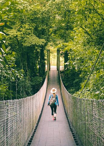 Eine Frau spaziert über eine Hängebrücke durch den Regenwald von Costa Rica