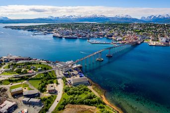 Luftansicht auf die Stadt und die Brücke in Tromso in Norwegen mit schneebedeckten Bergen im Hintergrund