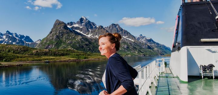Frau genießt die Aussicht auf die Berge an Deck des Hurtigruten-Schiffs MS Richard