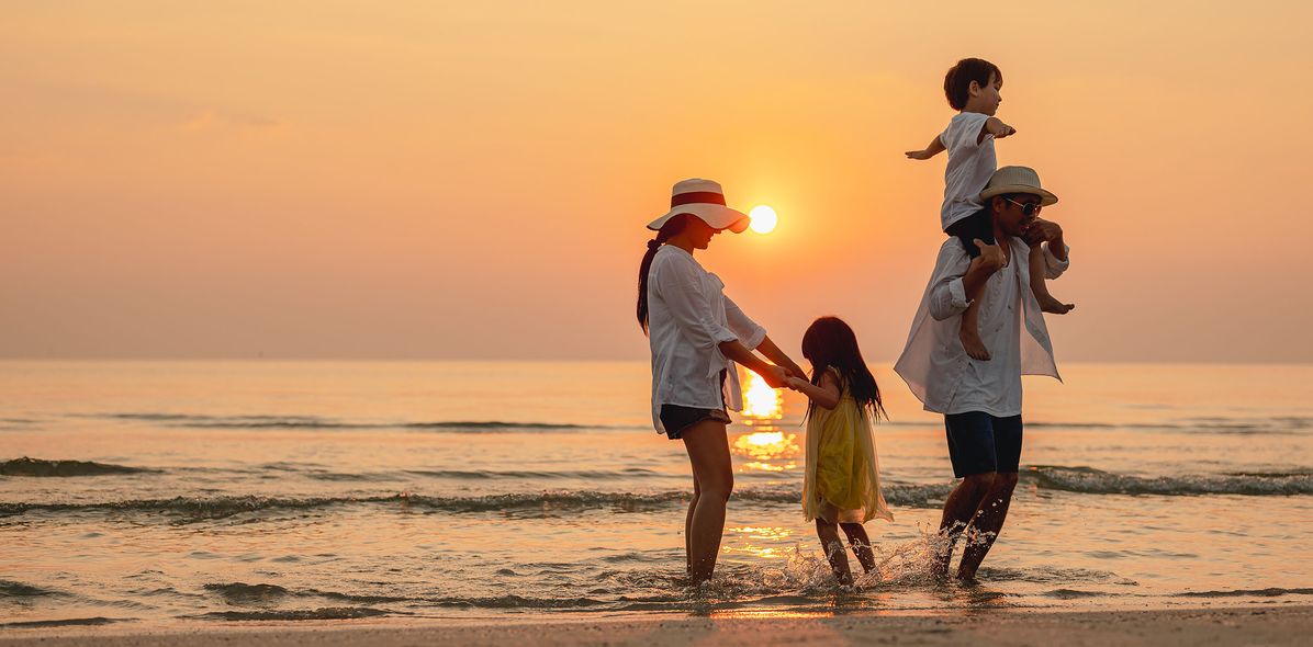 Familie in den Sommerferien bei Sonnenuntergang am Strand