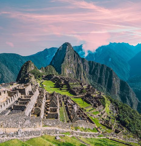 Machu Picchu im Abendlicht mit tiefem Tal und umliegenden Andenbergen