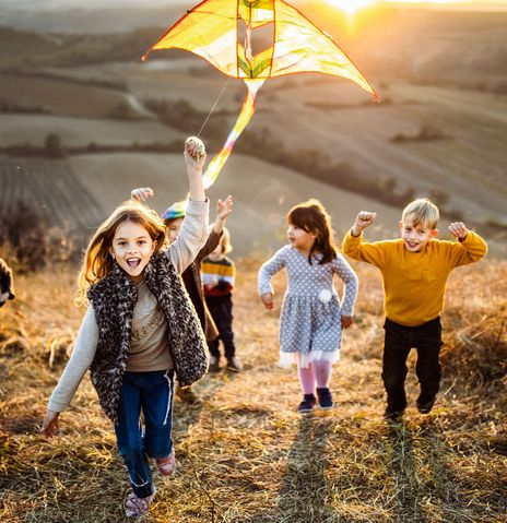 Kinder auf Feld mit Drachen Herbst