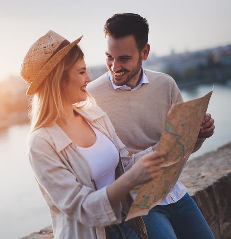 Verliebtes Paar schaut gemeinsam in eine Stadtkarte im Sonnenuntergang