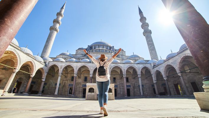 Frau steht im Innenhof einer Moschee in Istanbul mit Blick auf Kuppeln