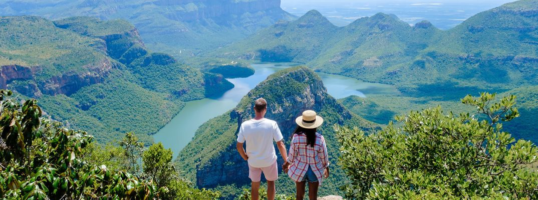 Zwei Reisende genießen den Panoramablick auf den grünen Blyde River Canyon in Südafrika