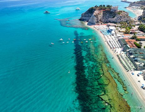 Blick aus der Luft auf den Strand von Tropea mit seinem kristallklaren Wasser und der Promenade, Kalabrien, Italien