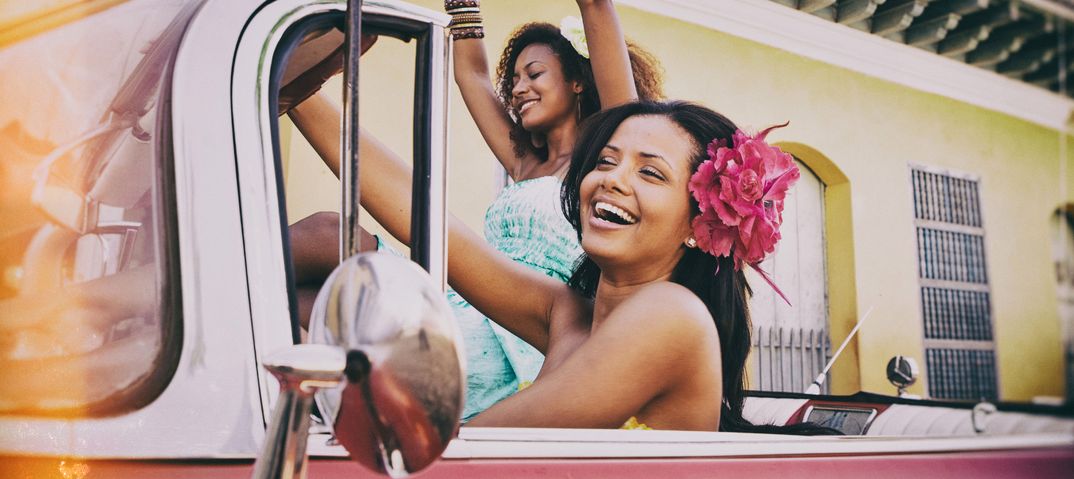 Lachende kubanische Frauen sitzen feiernd in einem Oldtimer