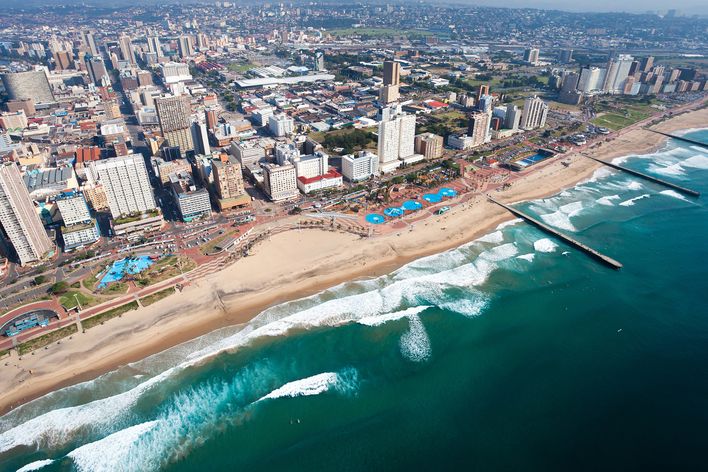 Luftaufnahme von Durbans langer Strandpromenade mit Hochhäusern und Wellen am Indischen Ozean