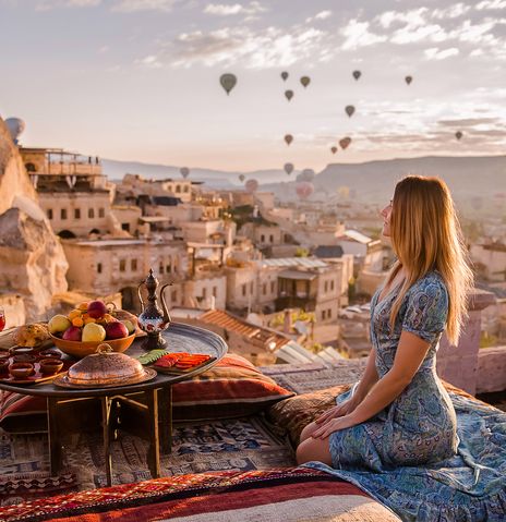 Frau mit Blick auf Felsenlandschaft und Heissluftballons