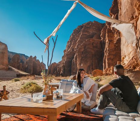 Reisende beim Picknick in der saudischen Wüste zwischen hohen Sandsteinfelsen