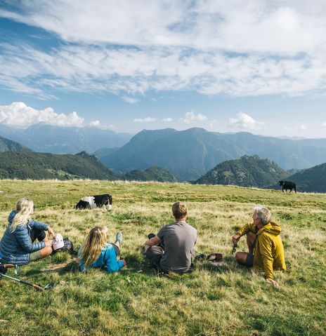 Menschen beim Picknick mit Blick auf Berge und Wiese.