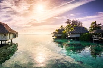Überwasser-Villen an einer tropischen Lagune im Abendlicht