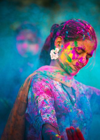 Frau feiert Holi-Fest in Indien mit bunten Farben im Gesicht