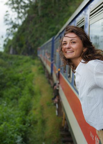 Frau lehnt sich bei der Fahrt aus einem Zug in Sri Lanka