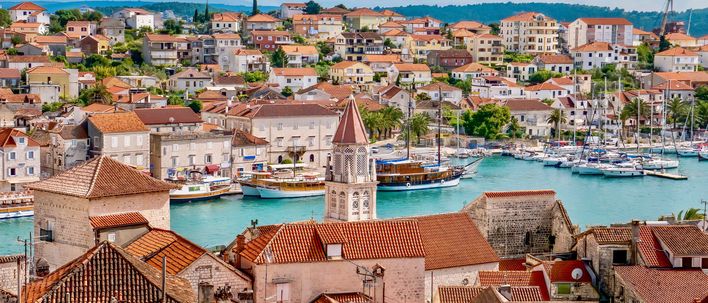 Blick auf die Altstadt von Trogir in Kroatien mit roten Dächern, Hafen und Booten im Vordergrund