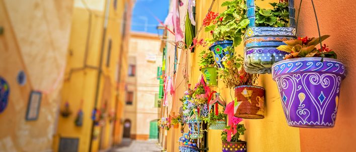Bunte Häuserfassaden und Blumen in einer Altstadtgasse auf Sardinien