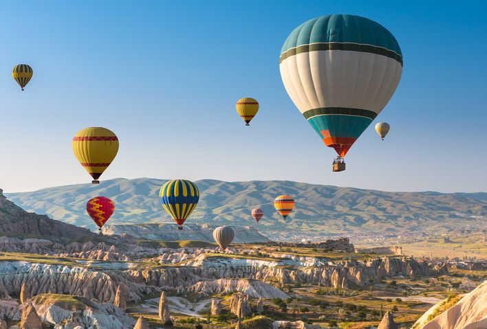 Heißluftballons steigen über Felsformationen in Kappadokien bei Sonnenaufgang