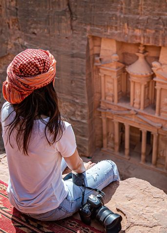 Frau blickt von Felsen auf das Schatzhaus in Petra