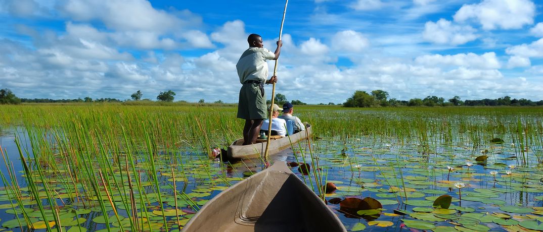 Touristen mit einem Guide auf einer Einboot-Safari im Okawango-Delta in Botswana
