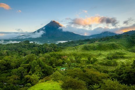Vulkan Arenal in Costa Rica bei Sonnenaufgang, umgeben von Nebel und üppigem Regenwald
