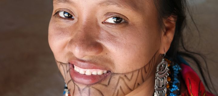 Porträt einer indigenen Frau aus Panama mit traditioneller Gesichtsbemalung und farbenfroher Kleidung