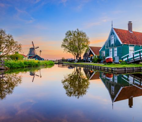 Idyllische Dorfkulisse mit Windmühle, Holzhäusern und spiegelndem Kanal in Zaanse Schans, Niederlande