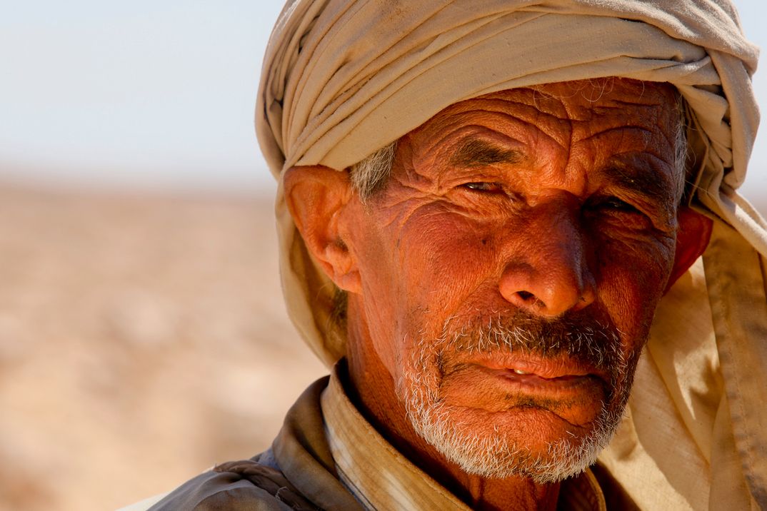 Ein Einheimischer Mann aus der Wüste Tunesiens mit einem Turban auf dem Kopf blickt direkt in die Kamera