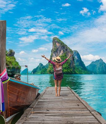 Frau auf Steg mit Boot in Thailand