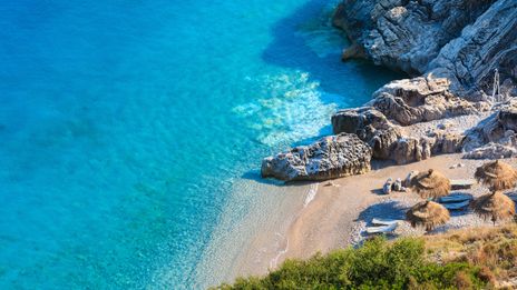  Der malerische Strand von Himare an der albanischen Riviera mit türkisfarbenem Wasser und Sonnenschirmen