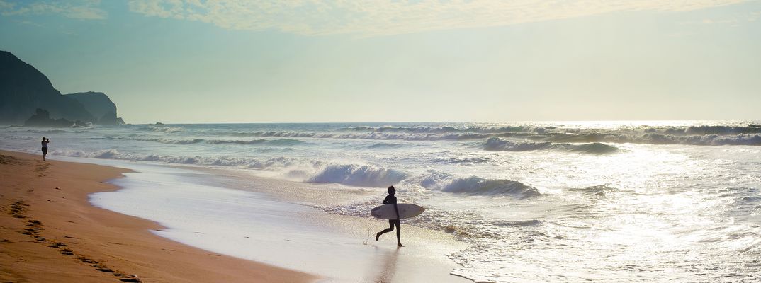 Surfer mit Surfbrett am Atlantikstrand in Portugal