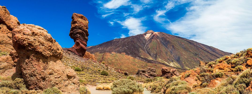 Vulkanische Felsformationen und der Pico del Teide unter blauem Himmel auf Teneriffa