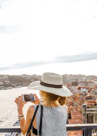 Frau fotografiert eine Stadt von einer hohen Plattform